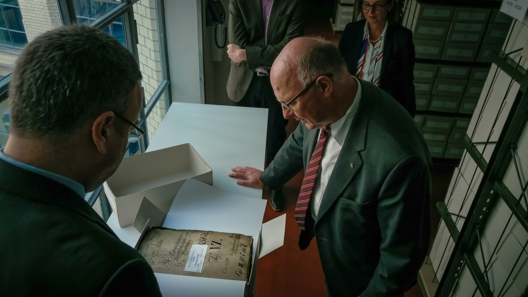 Staatssekretär Prof. Dr. Günther Schneider, Referatsleiterin 15 des Sächsischen Innenministeriums Frau Annette Rothenberger-Temme und Abteilungsleiter 2 des Sächsischen Staatsarchivs Herr Dr. Peter Wiegand begutachten eine Akte des Sächsichen Staatsarchiv