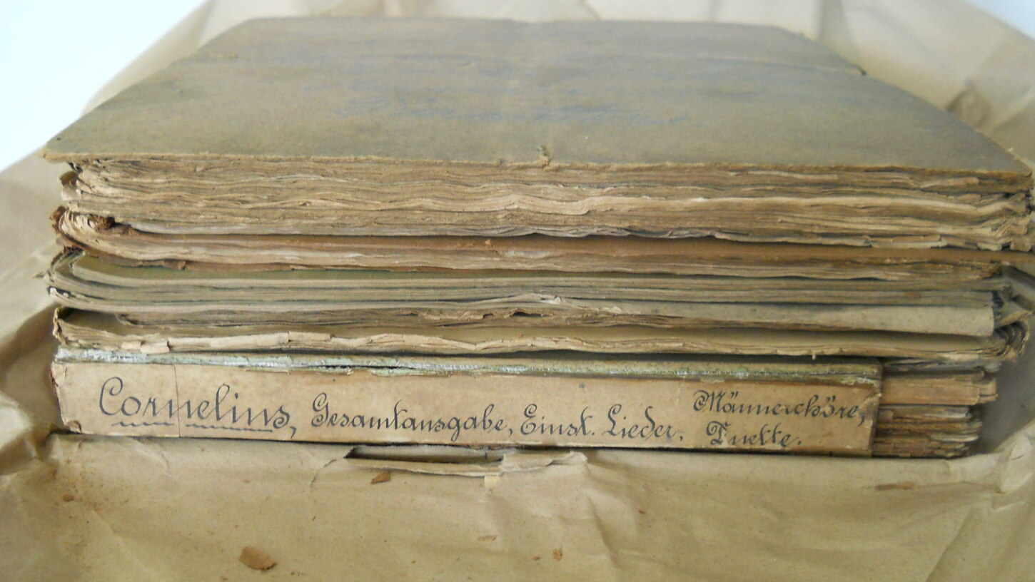 Buchband im aufgeschlagenem Packpapier, vorn handschriftlicher Titel