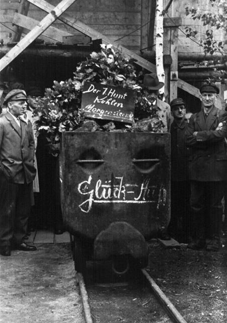 Personen stehen um Hunt anlässlich des Beginns der Förderung im Morgensternschacht 4 am 1. Juli 1948